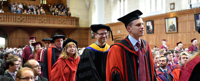 Members of staff process down the aisle in the graduation ceremony.